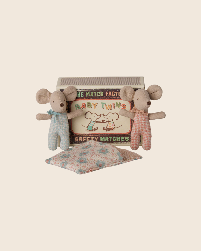 Two small PMaileg Twins, Baby Mice in Matchbox - Checker are dressed in pastel rompers and posed in front of their vintage-style matchbox bed labeled “Baby Twins,” with a patterned pillow placed beside them on a plain beige background.