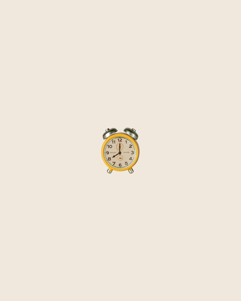 A small yellow vintage alarm clock with silver bells sits centered on a plain, light beige background, making it a charming accessory to complement the Maileg Family Room Set.
