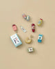 The Maileg Miniature Grocery Box offers a charming collection of mini food items like an ice cream cone, carton, and popsicle. Perfect for Maileg food set fans or pretend play, these artful toy foods are lively displayed on a beige background.