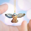 The limited-edition Kestrel Falcon Necklace features a handcrafted porcelain bird pendant with outstretched wings, suspended from a gold chain and showcased between two open hands against a softly blurred background.