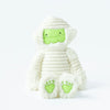 A glow-in-the-dark Slumberkins Halloween Gift Set - Mummy Kin plush toy, with white fabric wrappings and lime green accents on the feet and face, sitting against a white background.