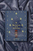 A blue hardcover, "The Nutcracker | Collector's Edition," rests on silky dark fabric. Ballet motifs with a Christmas tree, nutcracker, candles, and mice border the cover of this classic fairy tale.