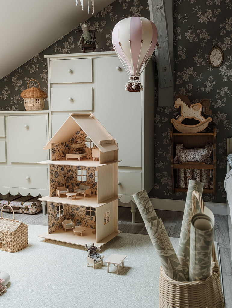 A cozy, vintage-style children’s room featuring handmade decor, a wooden dollhouse, wicker baskets, a toy rocking horse, and the Hot Air Balloon - Lilac with its wooden basket, all set against floral wallpaper.