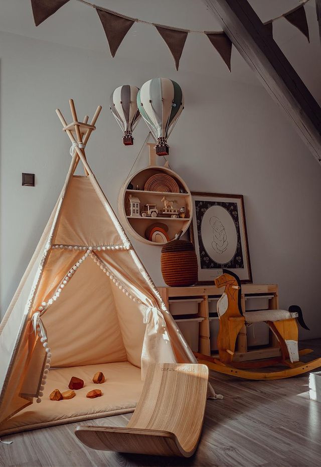 A cozy children’s playroom with a beige teepee tent, wooden toys, a rocking horse, a balance board, wall shelves with handmade decor, and whimsical Hot Air Balloon - Mint Green and Grey decorations hanging from the ceiling.