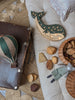 A cozy scene with a vintage suitcase, green whale-shaped night light, Hot Air Balloon - Light Brown / Green decor, wooden blocks, wicker basket, and fabric rabbit doll on a textured rug—perfect for charming children's room decoration.
