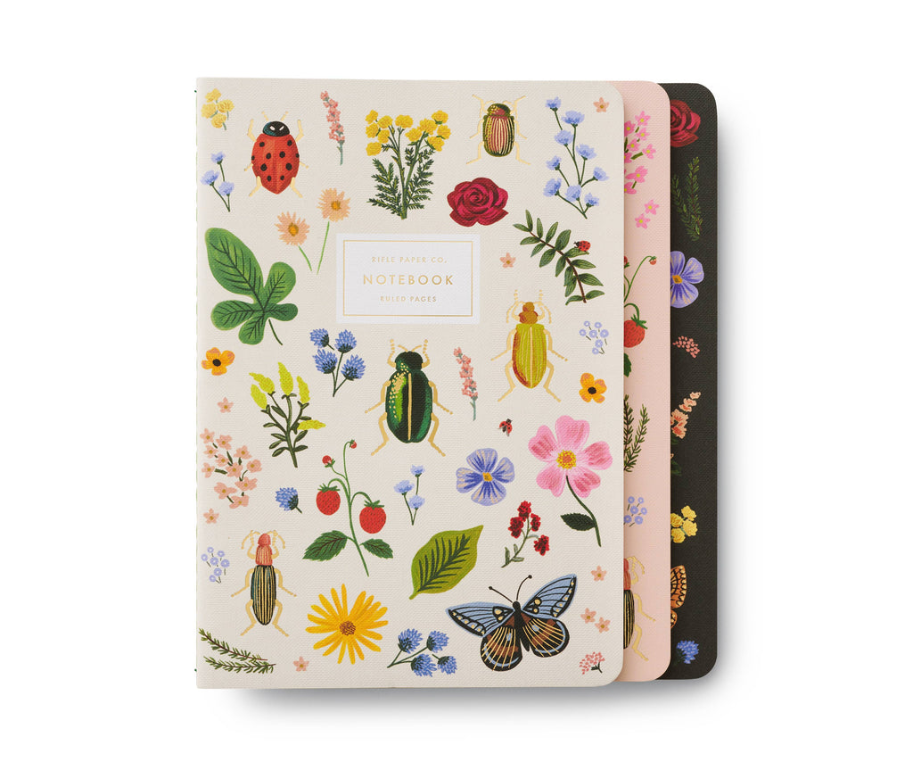 The Assorted Set of 3 Curio Notebooks features decorative covers with flowers, beetles, a butterfly, and a ladybug. The front gold foil notebook has a white background with "Notebook" centered on the cover.