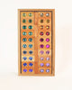 Wooden tray filled with two columns of Bauspiel Large Gem Blocks, 45-Piece Set, each featuring a colorful, faceted plastic gem in the center.