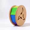 Grimm's Sound and Color Wheel is a non-toxic wooden baby motor skill toy with a cylindrical shape, green, blue, and purple segments, musical note cutouts, and stands upright on a white background.