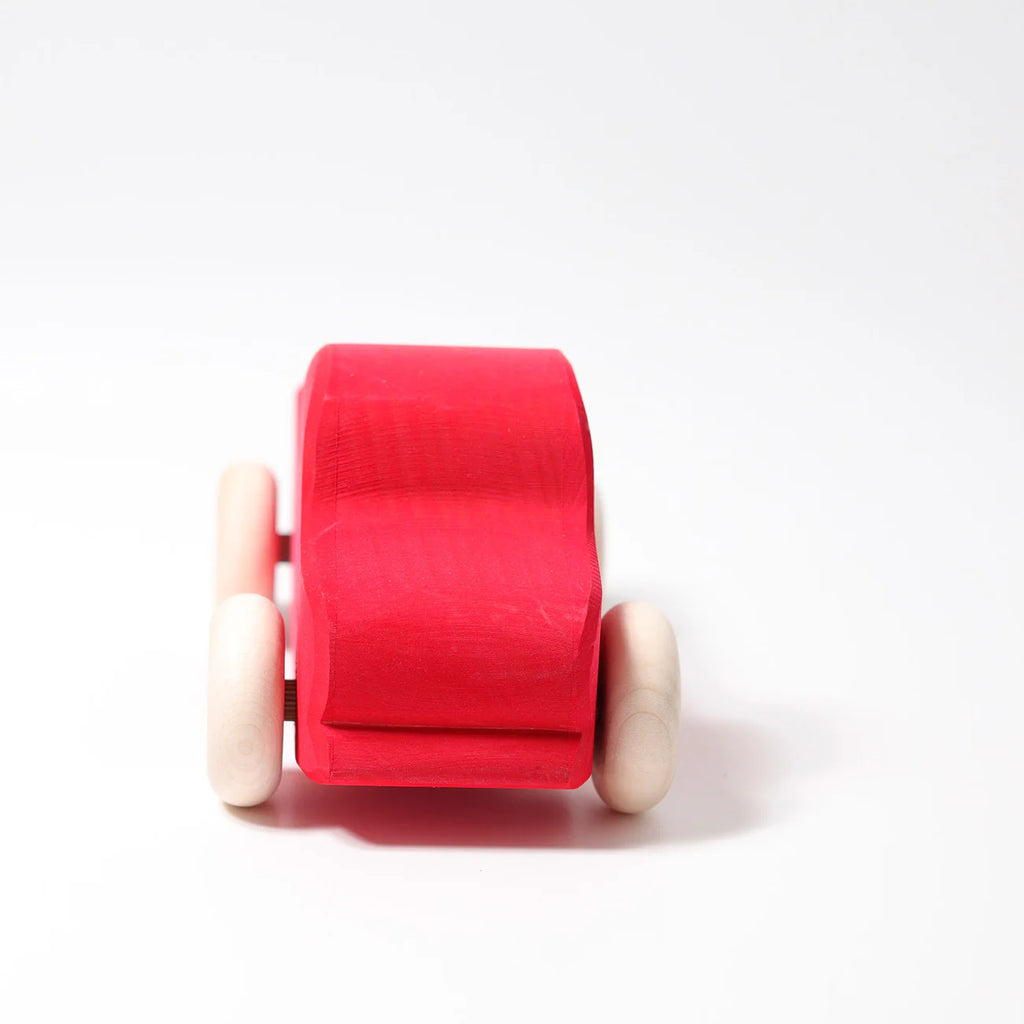 Grimm's Large Red Truck is a simple, non-toxic wooden toy featuring a red body and natural-colored wheels, shown against a plain white background.