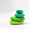 A minimalist stack of four smooth, oval-shaped stones painted in gradient green shades, from light green at the bottom to teal at the top, set against a plain white background. These organic stone shapes evoke a sense of tranquility and balance. The Moss Pebbles Stacker is perfect for fostering a calming and harmonious environment.