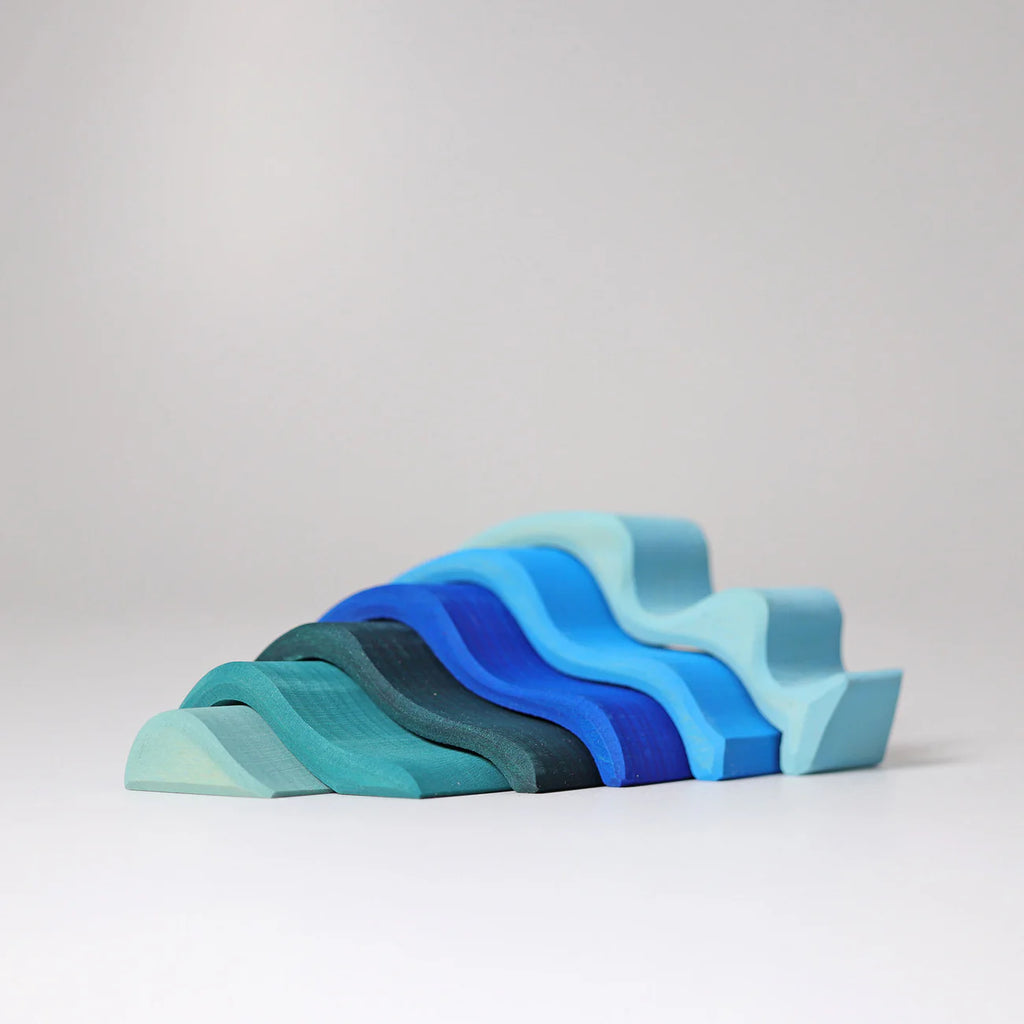 The Grimm's Ocean Waves, Small features curved, wave-shaped wooden blocks in blue and teal shades, arranged in a layered stack on a white background—a striking toddler stacking toy.