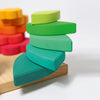 Two stacks of colorful, petal-shaped wooden pieces from the Grimm’s Stacking Game Shapes arranged on a wooden base as a stacking toy.