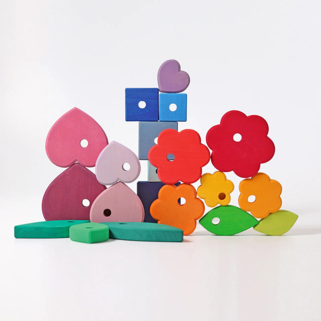 Grimm’s Stacking Game Shapes: a stack of colorful, geometric wooden hearts, flowers, squares, and leaves used as a stacking toy.