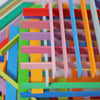 Colorful Grimm's Leonardo da Vinci Building Sticks resembling a children's building toy are arranged in a crisscross pattern, creating a visually intricate and playful composition. The arrangement, akin to Leonardo da Vinci constructions, features varied shades overlapping in a seemingly random yet cohesive manner.