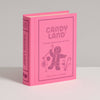 The Board Game: Candy Land Vintage Bookshelf Edition comes in a pink hardcover featuring classic CANDY LAND artwork with a gingerbread person, lollipop, and candy cane—ideal for fans of the vintage board game. Stands upright on any surface.