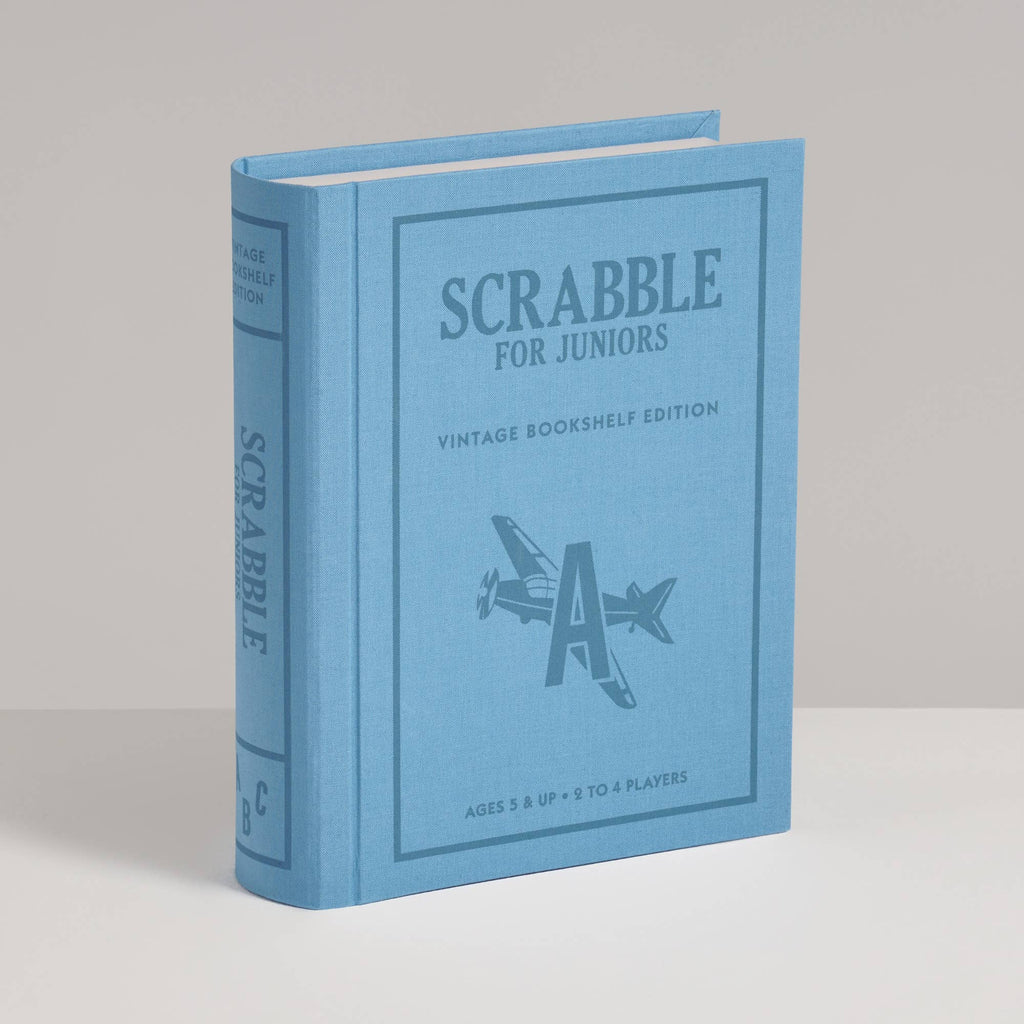 Light blue Scrabble for Juniors Vintage Bookshelf Edition game box shaped like a book, featuring an airplane icon on the cover.