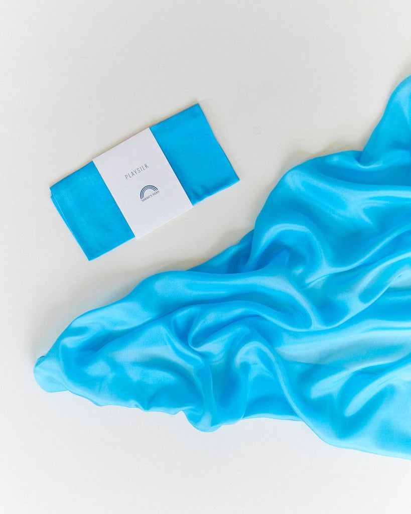 Sarah's Silks Solid Color Playsilk in Turquoise, made of pure silk, is presented folded in white packaging and alongside a matching draped cloth—ideal for open-ended play—displayed on a white surface.