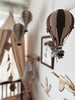 A nursery decorated in soft brown and beige tones features the Light Brown / Dark Brown Hot Air Balloon mobile, wooden bird wall art, and a cozy crib canopy—perfect for children's room decor.
