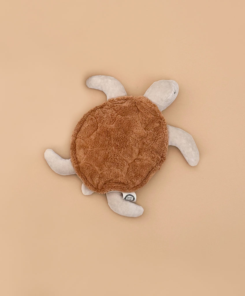 The Senger Naturwelt Cuddly Animal - Turtle, with a soft brown shell and beige flippers, made from organic cotton as a grain pillow, is displayed on a plain light brown background.
