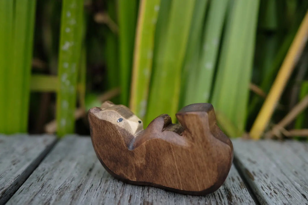 A Handmade Holzwald Bear Cub - Lying, a carved wooden toy of a bear cub lying on its back, perfect for imaginative play.