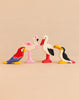 Four handcrafted birds from the Holztiger Handmade Wooden Birds of the World Set—a parrot, flamingo, stork, and toucan—standing in a row.