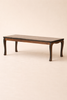 The Maileg Dining Room Set features a low rectangular table with a dark finish and elegant curved legs, displayed against a plain light beige background.