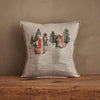 The Coral & Tusk Winter Foxes Pocket Pillow showcases embroidered fox, bear, and wolf figures among pine trees with snowy accents—ideal winter fox decor on a wooden surface.