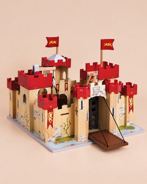 Introducing the Lionheart Wooden Castle—a sustainable toy designed for hours of imaginative adventure! This beautifully crafted wooden castle features striking red battlements, flags adorned with a yellow lion, a functional raised drawbridge, and charming painted details of vines and stones on a beige background—perfect for inspiring creative play.