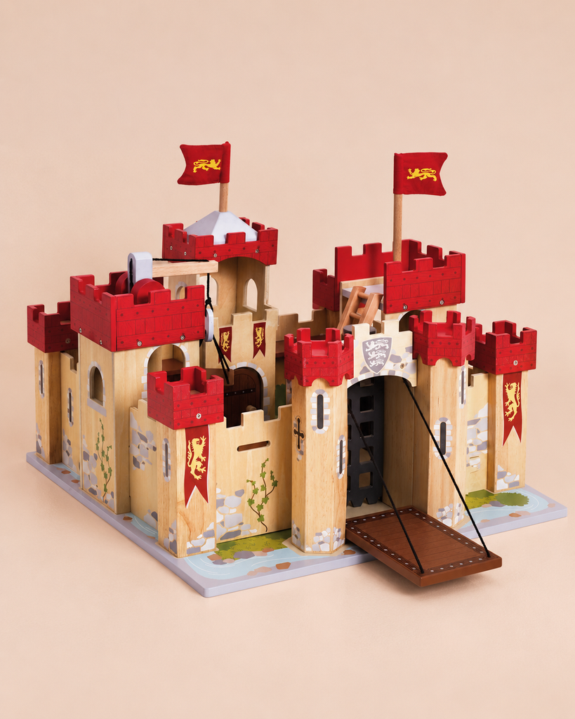 Introducing the Lionheart Wooden Castle—a sustainable toy designed for hours of imaginative adventure! This beautifully crafted wooden castle features striking red battlements, flags adorned with a yellow lion, a functional raised drawbridge, and charming painted details of vines and stones on a beige background—perfect for inspiring creative play.