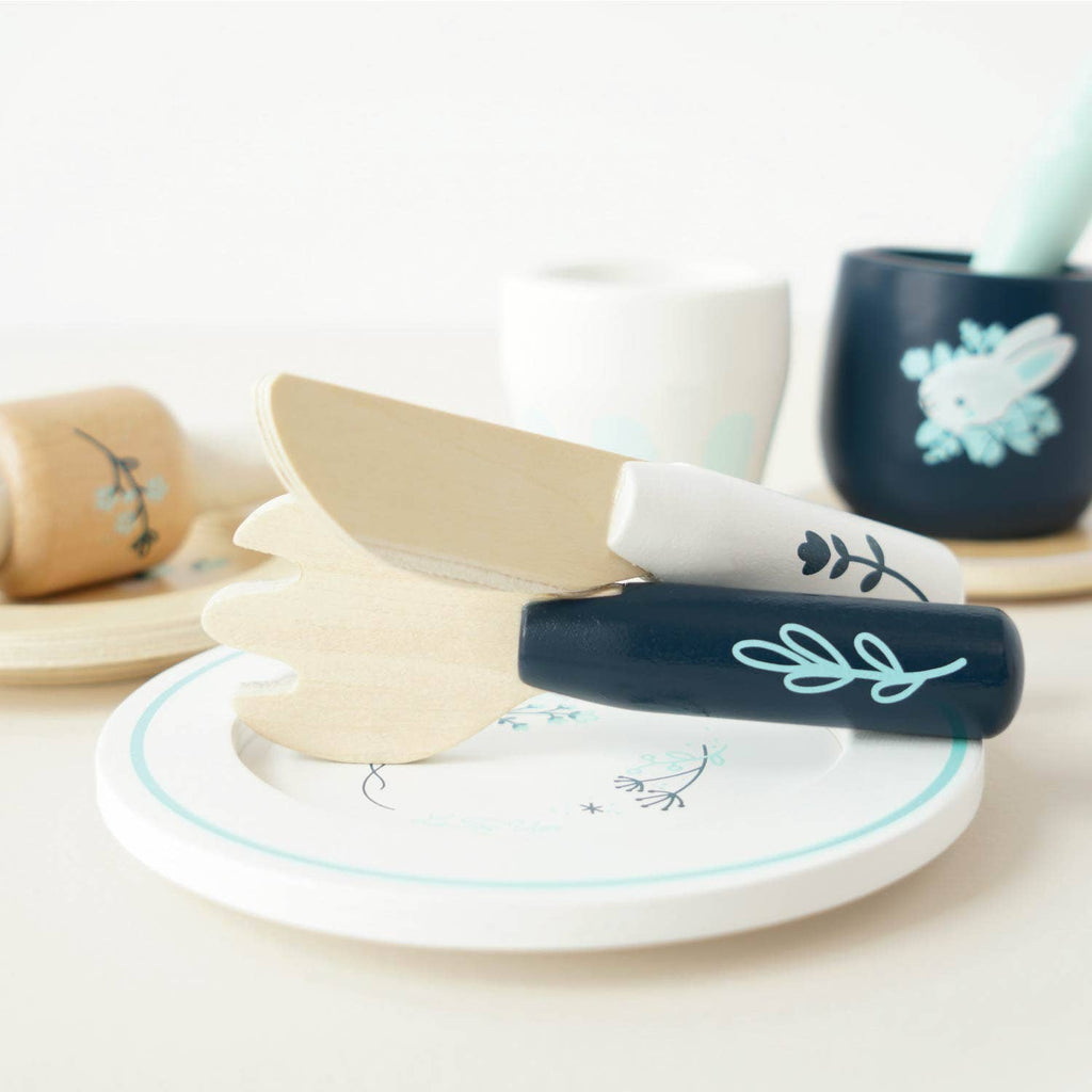 A wooden toy knife and fork from the Cutlery & Dinner Set with painted handles resting on a matching plate for pretend play.