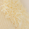 Close-up of Cuddle + Kind Flora the Duckling - Ivory, featuring soft, shaggy ivory fibers for a fuzzy look—perfect for crafting heirloom-quality dolls or unique fair trade gifts. Background is smooth and matches the fabric’s color.
