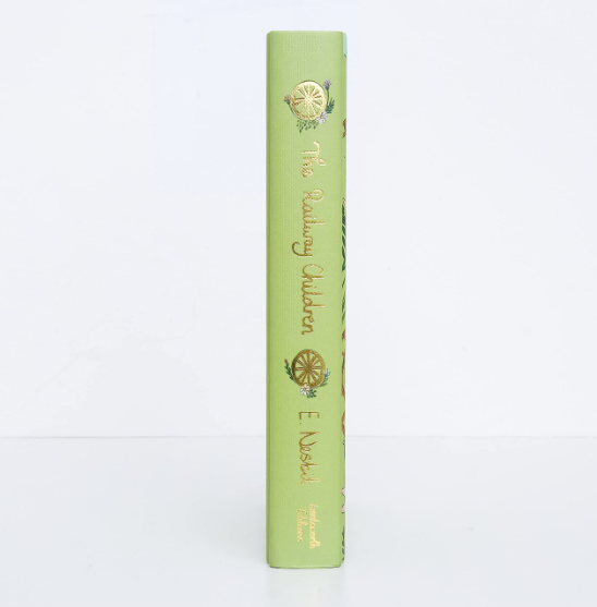 A green hardcover Collector’s Edition of "The Railway Children" by Edith Nesbit, featuring gold embossed text, a floral pattern, and a railway wheel illustration on the spine.