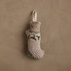 The Coral & Tusk Puppy Stocking Ornament, featuring red stripes, a green patch, holly embroidery, and a dog in a sweater, hangs by a white loop—a charming holiday decoration for your home.