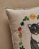 The Coral & Tusk Kitten Cameo Pillow features a beige linen cover with embroidered flowers and a partial black and white cat in a red collar, making it perfect for springtime decor on any neutral background.