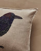 The Coral & Tusk Blackbird with Acorn Pillow features soft beige linen, a black and purple embroidered blackbird on the left, and a plain Oeko-Tex certified surface for eco-friendly comfort.