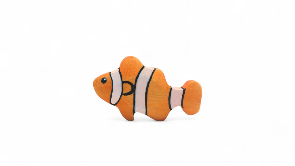 The Handmade Holzwald Clownfish is a small, handcrafted wooden toy painted orange with white and black stripes, resembling a clownfish. It sits on a plain white background and is part of the Holzwald toys collection.