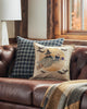 A cozy autumn-themed living room corner featuring a plush leather sofa adorned with a Supermoon Spell Pillow showcasing a witch and owl design, beside a window with a fall view. A plaid throw blanket adds warmth.