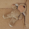 The Olli Ella Cozy Dinkum Doll - Lamby Pip, in a fuzzy brown lamb suit with closed eyes and a small rainbow on its chest, is resting peacefully on a matching textured blanket.