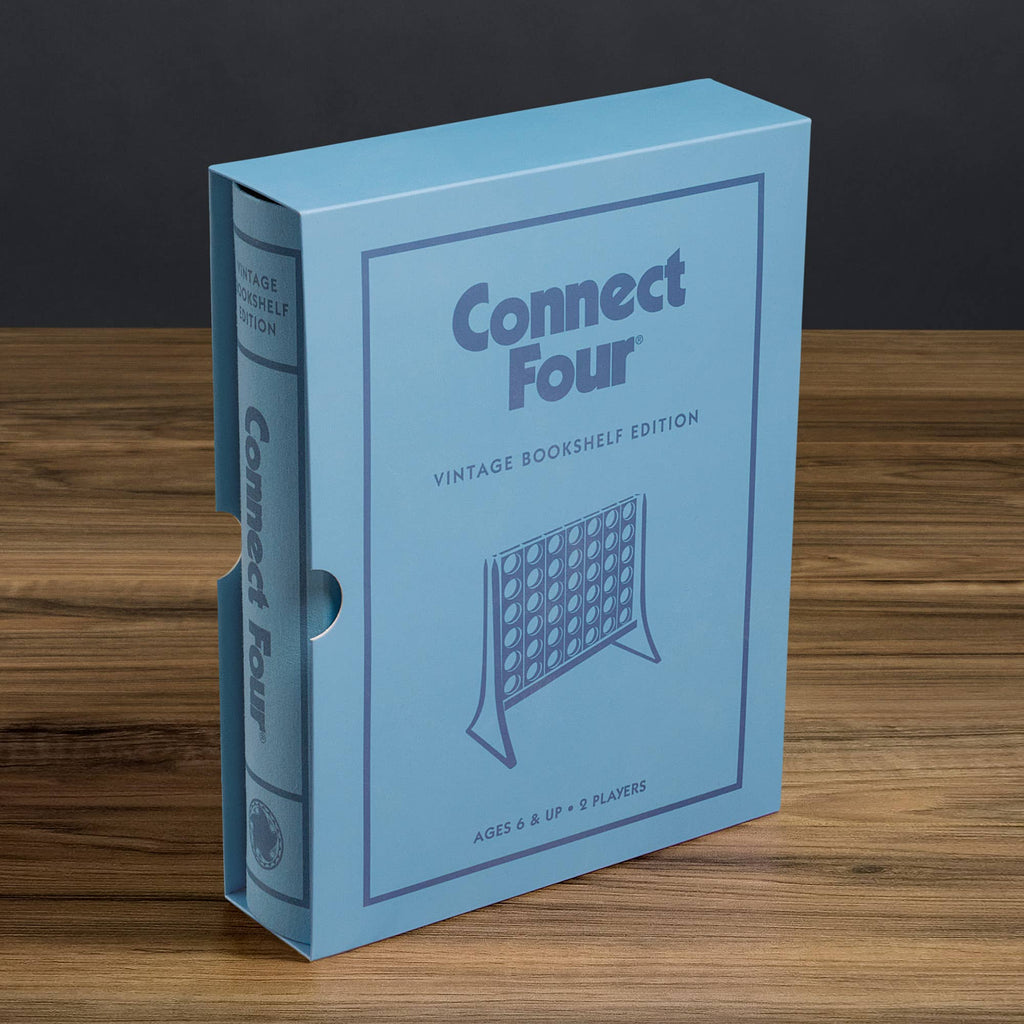 A blue, book-shaped box labeled "Board Game: Connect 4 Vintage Bookshelf Edition" rests on wood. This collectible resembles a classic hardcover book and features an illustration of the iconic vertical strategy game.
