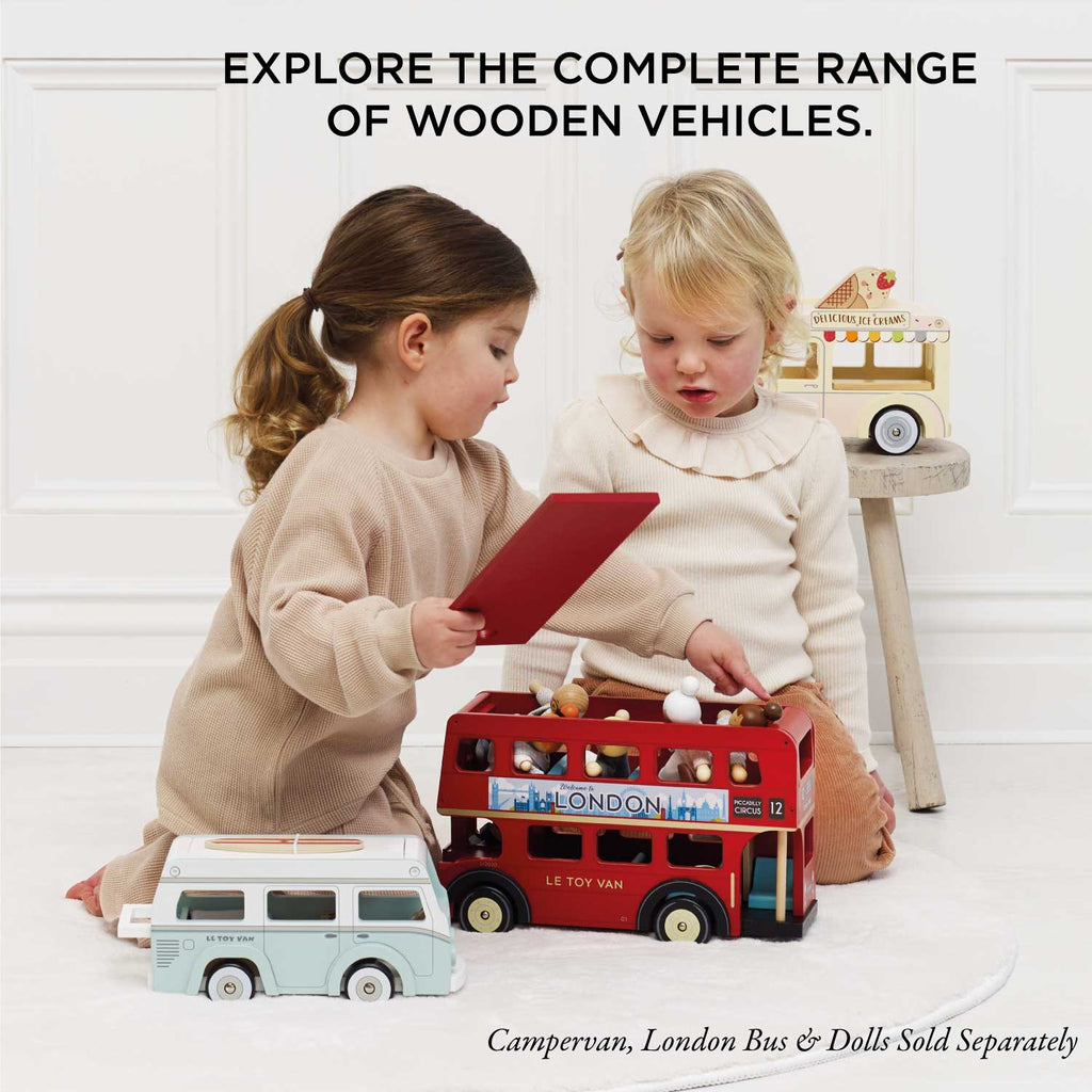 Two young children play with wooden vehicles, like a red London bus, a vintage campervan, and the Wooden Ice Cream Van (ships in one week), beneath text: "Explore the complete range of wooden vehicles.