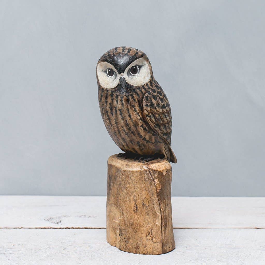 The Hand Carved Ornament - Saw Whet Owl - 10"H features detailed feathers and large eyes, perched on a sustainable softwood base against a light gray background.