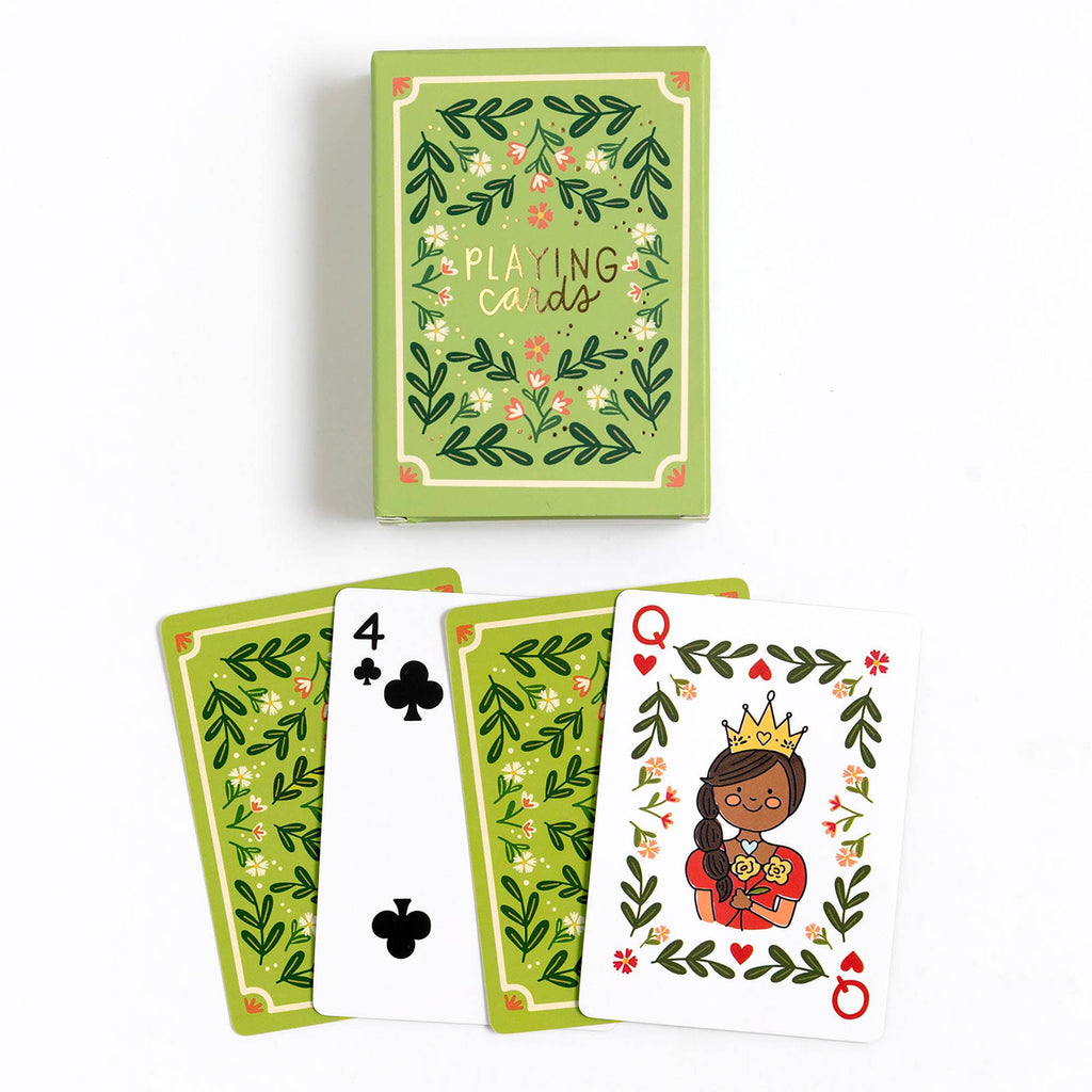 A box of Green Floral Deck of Playing Cards (ships in approximately one week) sits above three cards—4 of clubs, queen of hearts with a cartoon crowned woman, and the card back—all featuring matching green floral designs.