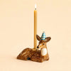 The Deer Cake Topper - Final Sale (ships in one week) is a handcrafted ceramic figurine with a blue and white striped party hat and a lit candle, perfect as a charming porcelain cake topper.