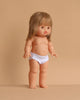 The Minikane Standing Doll (14") - Zoelie features light skin, straight blonde hair with bangs, and white underwear. Anatomically correct and made in Spain, Zoelie stands upright against a plain beige background. Clothing sold separately.
