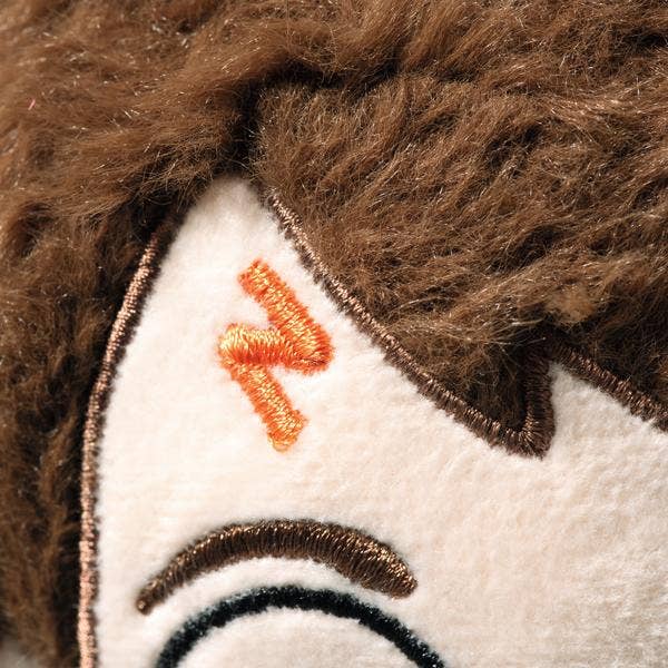 Close-up of a Steiff Harry Potter Plush 11" face featuring brown embroidered hair, an orange embroidered "N" shape on the side of the head, and part of an eyebrow stitched with brown thread.