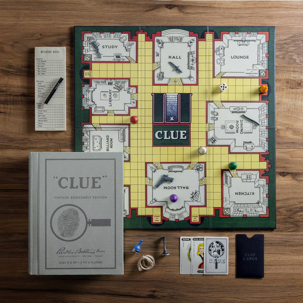 The Clue Vintage Bookshelf Edition, with its premium board, pieces, dice, cards, notebook, pen, and weapon tokens, is set up on a wooden table—ready for crime solvers to begin their mystery adventure.