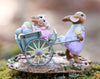 The Wee Forest Folk Tiny Collectible - Easter's on its Way (Not a Toy) is a hand-sculpted miniature featuring a bunny in pastels pushing a blue wheelbarrow with colorful eggs and two small bunnies, set on a floral base.