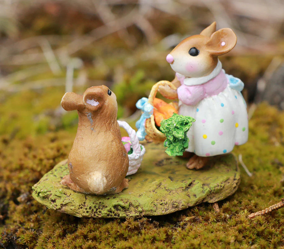 Two small, charming Wee Forest Folk Tiny Collectible mouse figurines—Baskets Full of Easter Joy—stand on green moss. One wears a white dress with colorful dots and holds a veggie basket; the other sits facing her with a smaller basket.