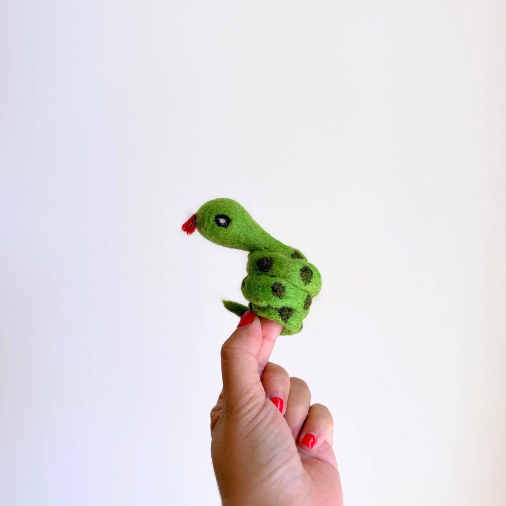 A hand with red-painted nails holds the Snake Finger Puppet—green with black spots and a red tongue—ideal for creative storytelling and imaginative play, shown against a plain white background.