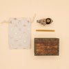 A star-patterned drawstring pouch, a gold pen, an Elephant Cake Topper - Final Sale (ships in one week), and a wooden box labeled “camptellow” are arranged neatly on a beige background.